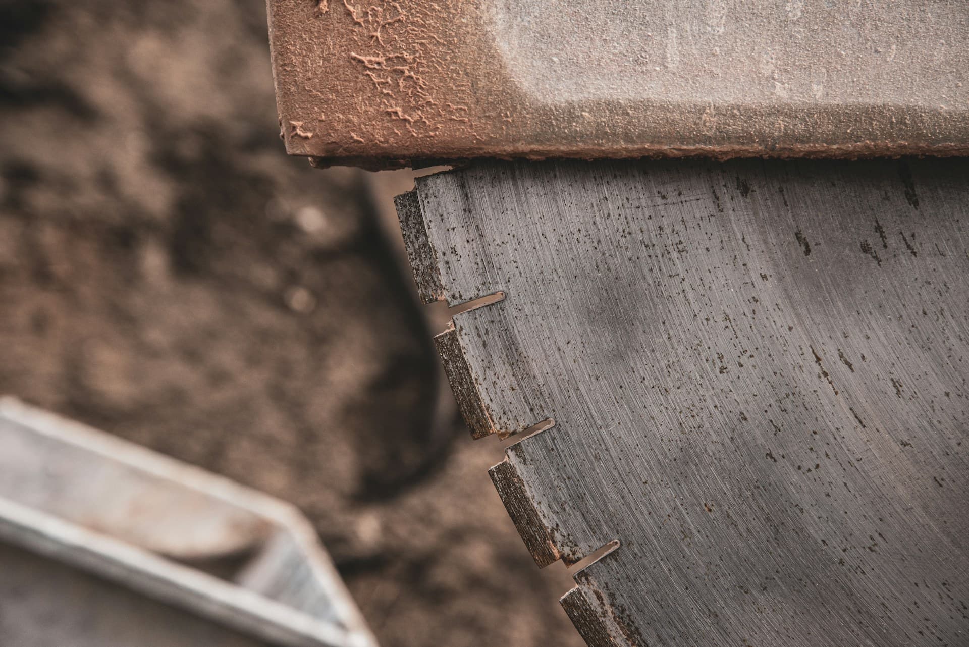 Close-up of a diamond-segmented circular saw blade beside a cut concrete kerb