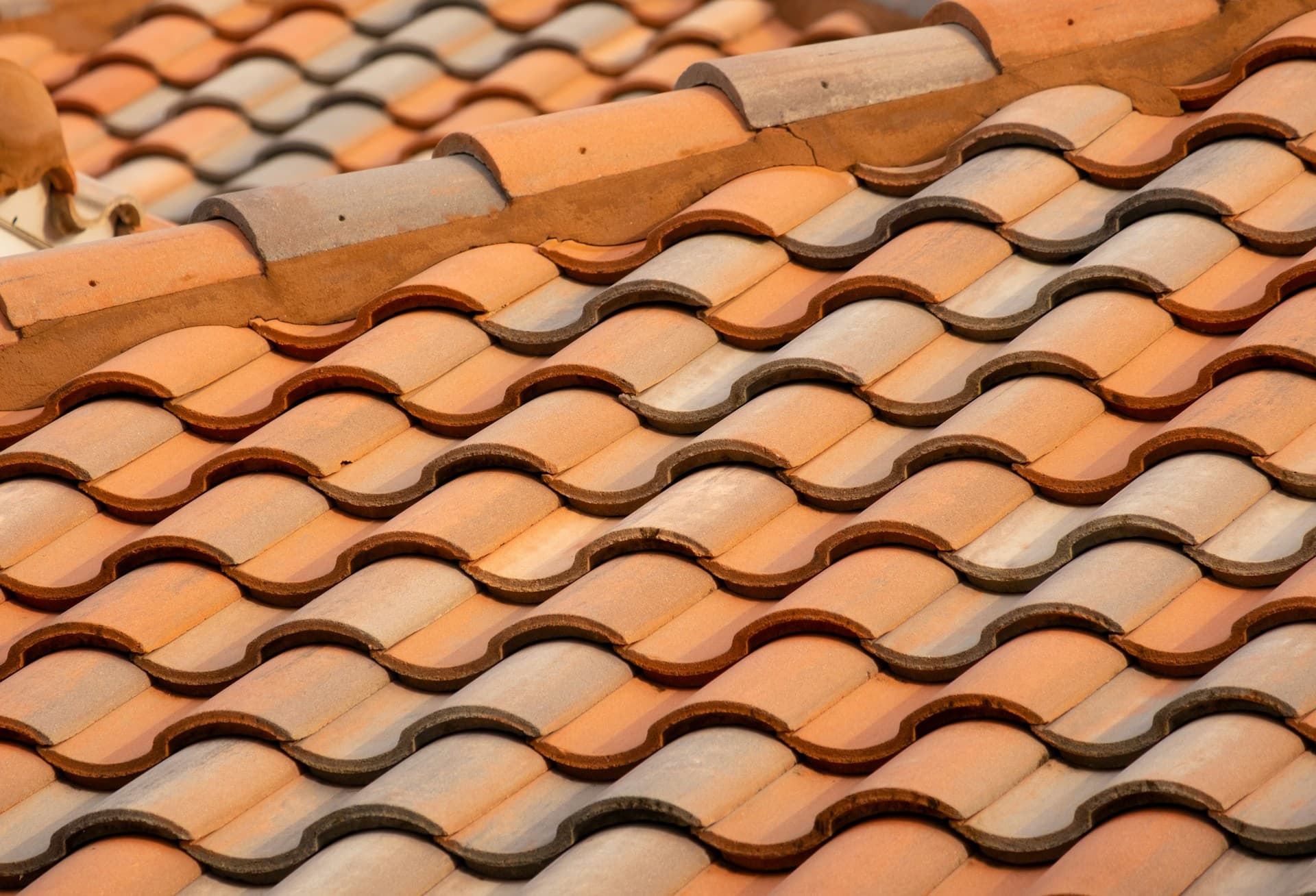 Close-up of overlapping terracotta clay roof tiles with ridge capping