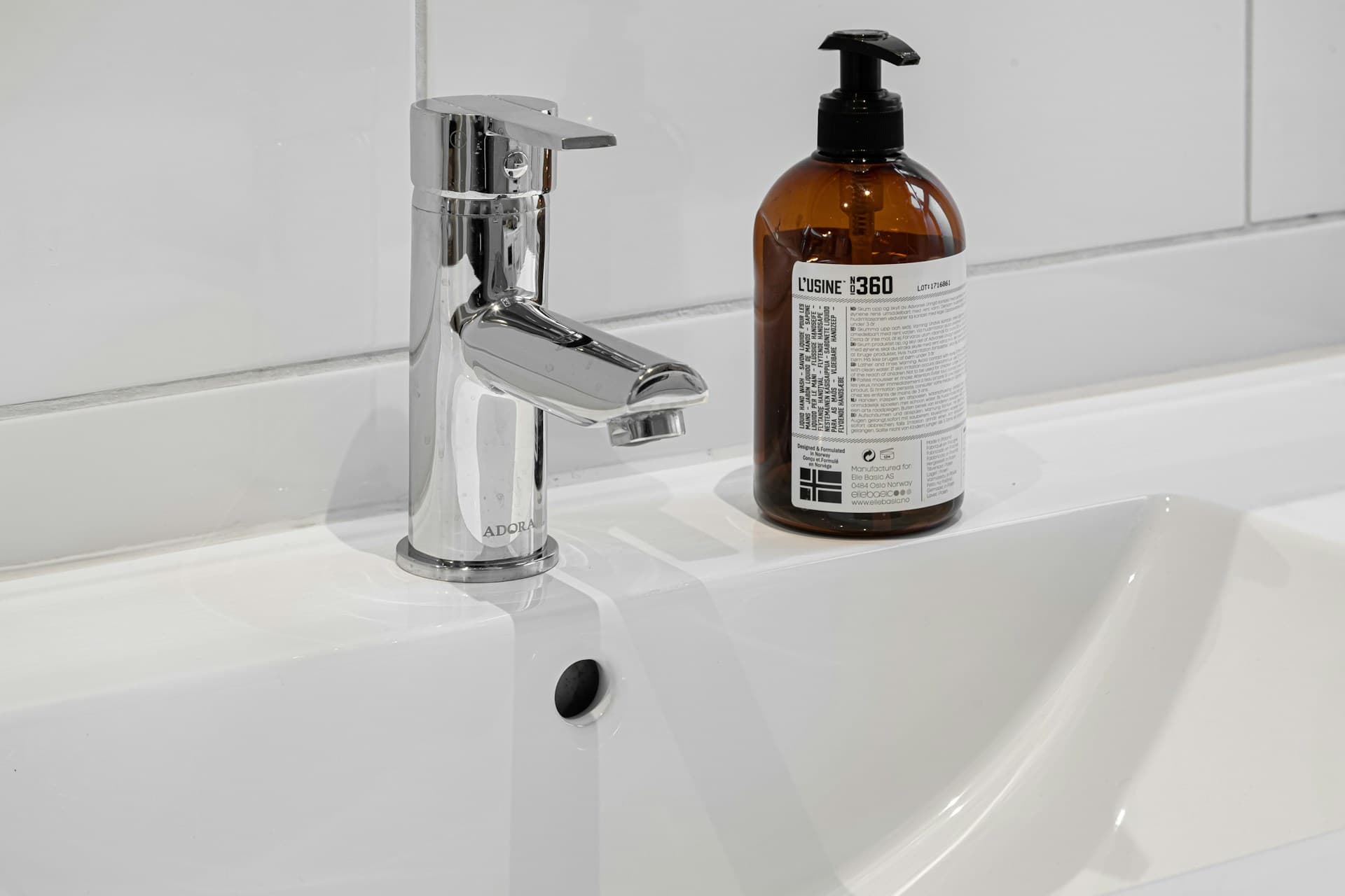 Chrome single-lever basin mixer tap on a white ceramic vanity with soap dispenser