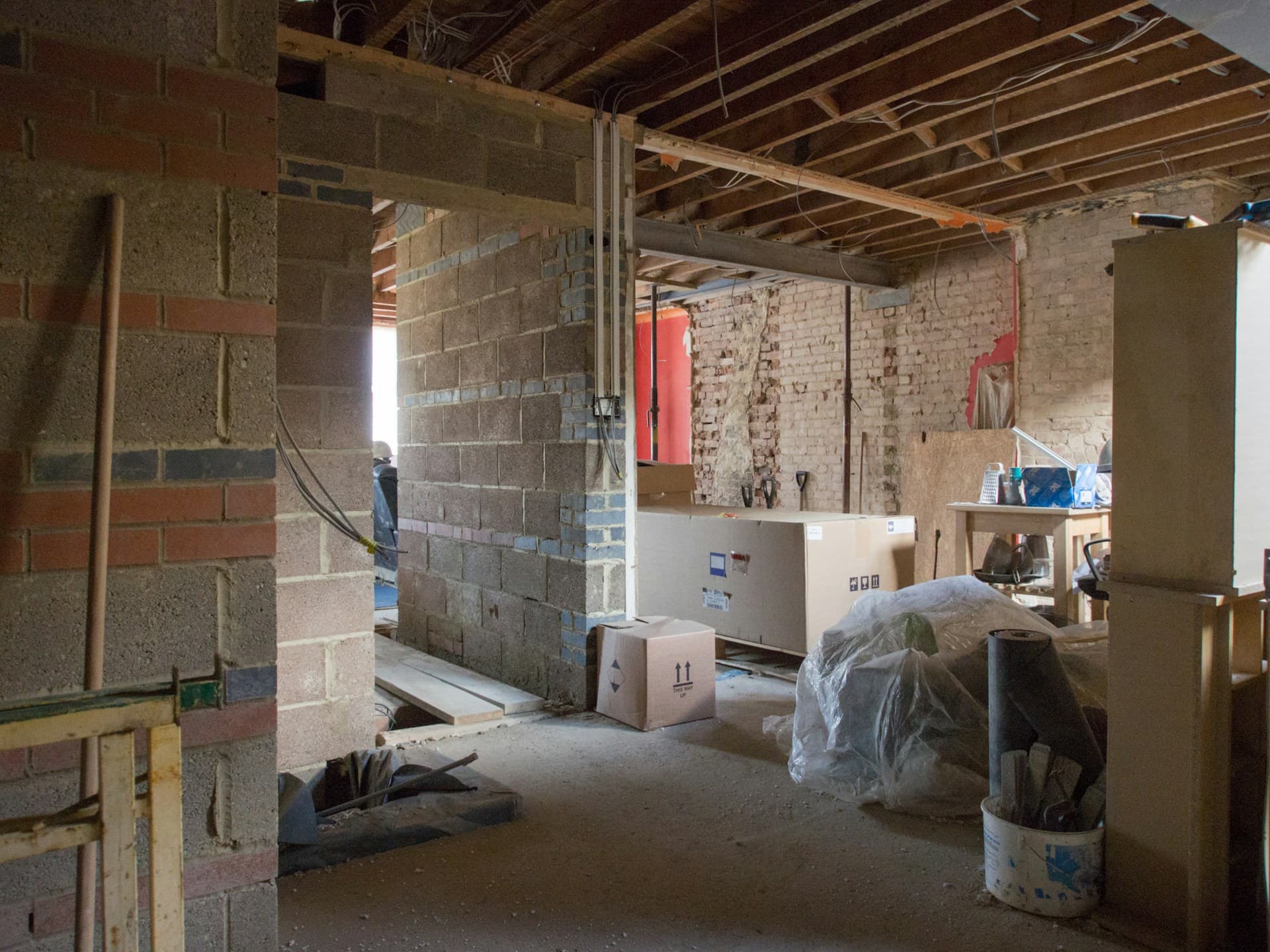 Gutted interior with exposed brickwork, blockwork and stripped ceiling joists mid-renovation