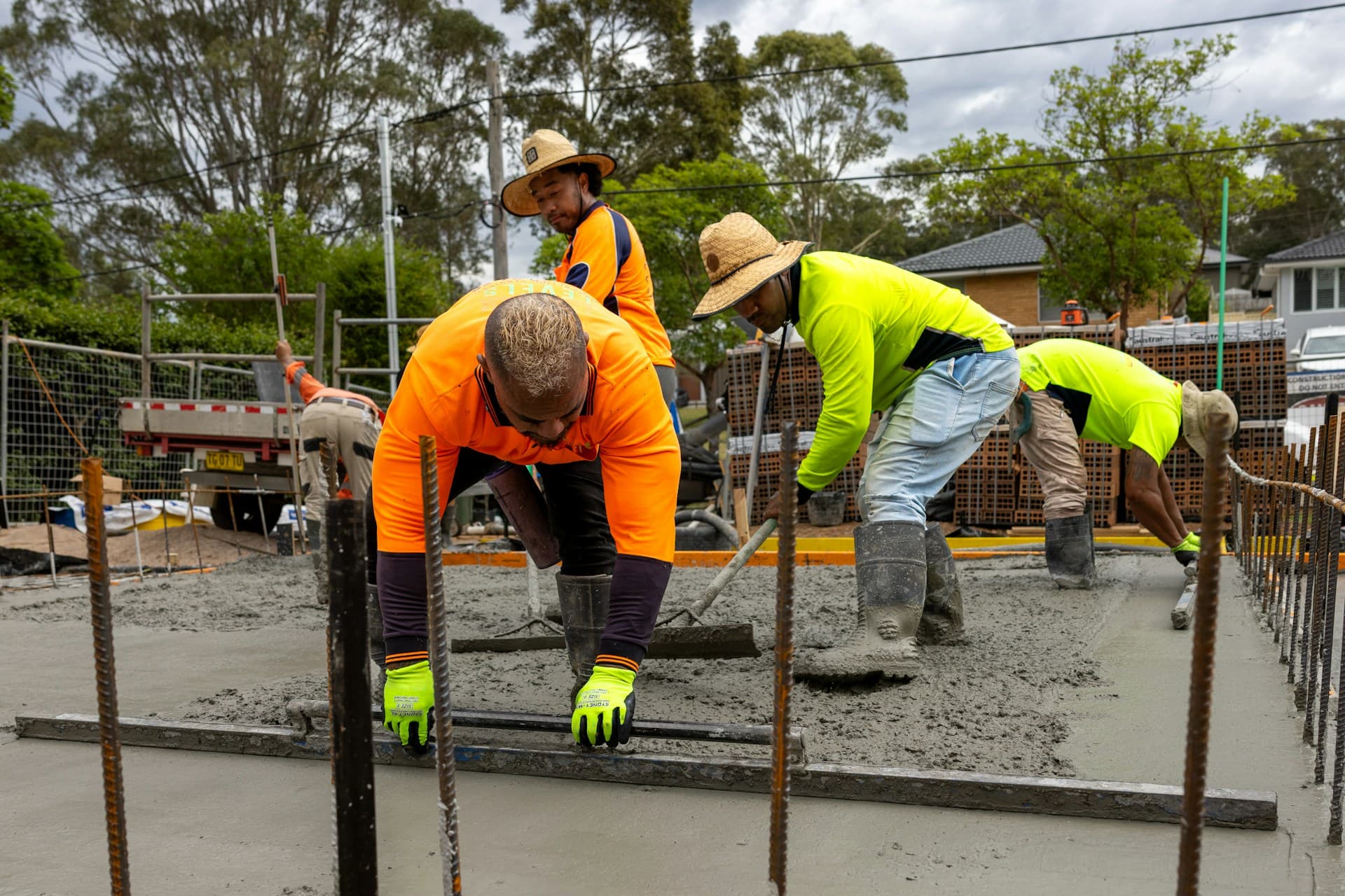 Workers in hi-vis screeding wet concrete over steel reinforcement on site