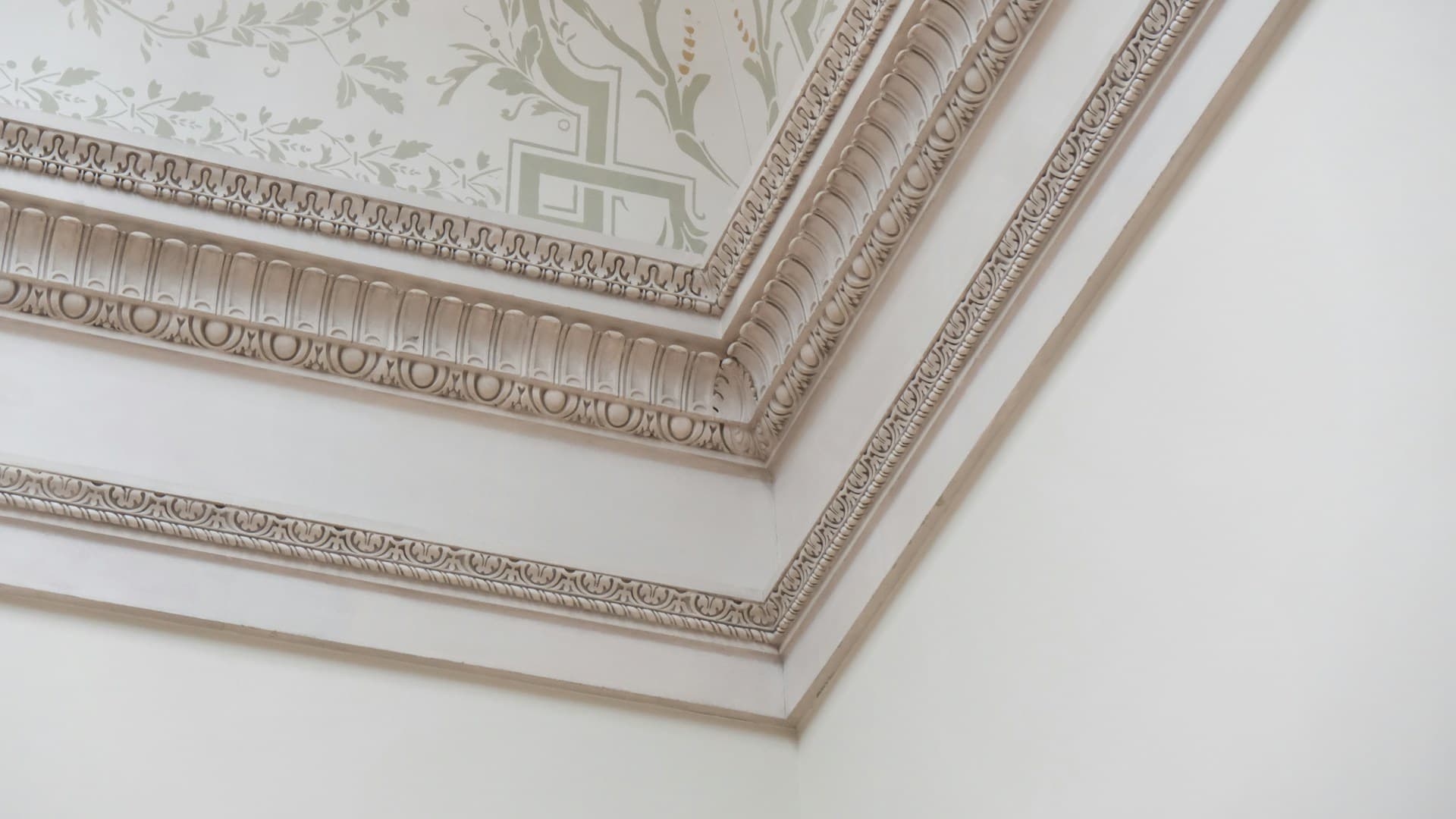 Ornate moulded plaster cornice meeting a decorative painted ceiling in a corner