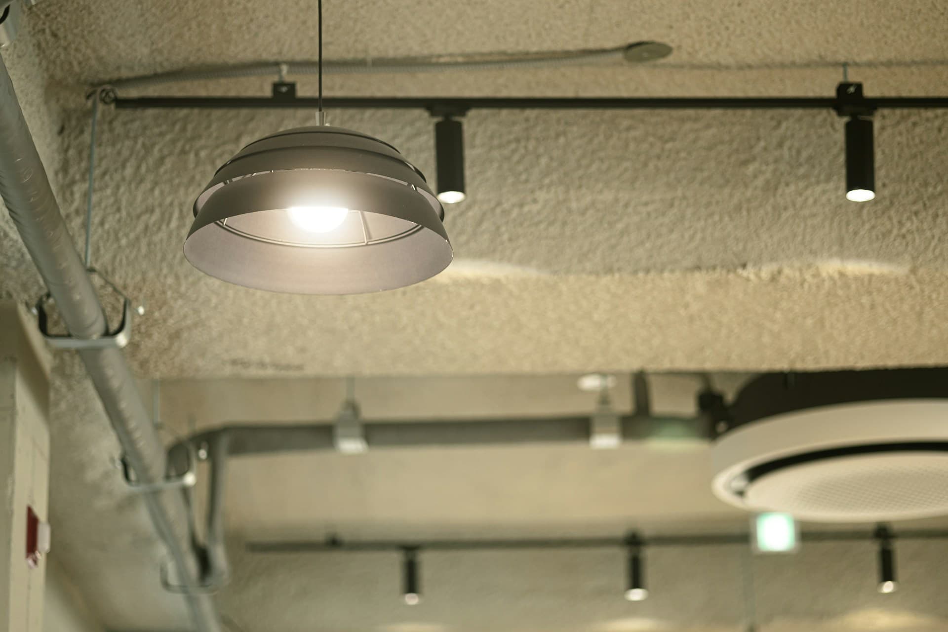 Hanging dome pendant light and track spotlights on an exposed industrial ceiling